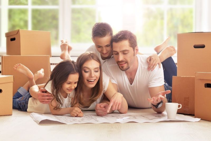 family of four smiling while sitting on couch
