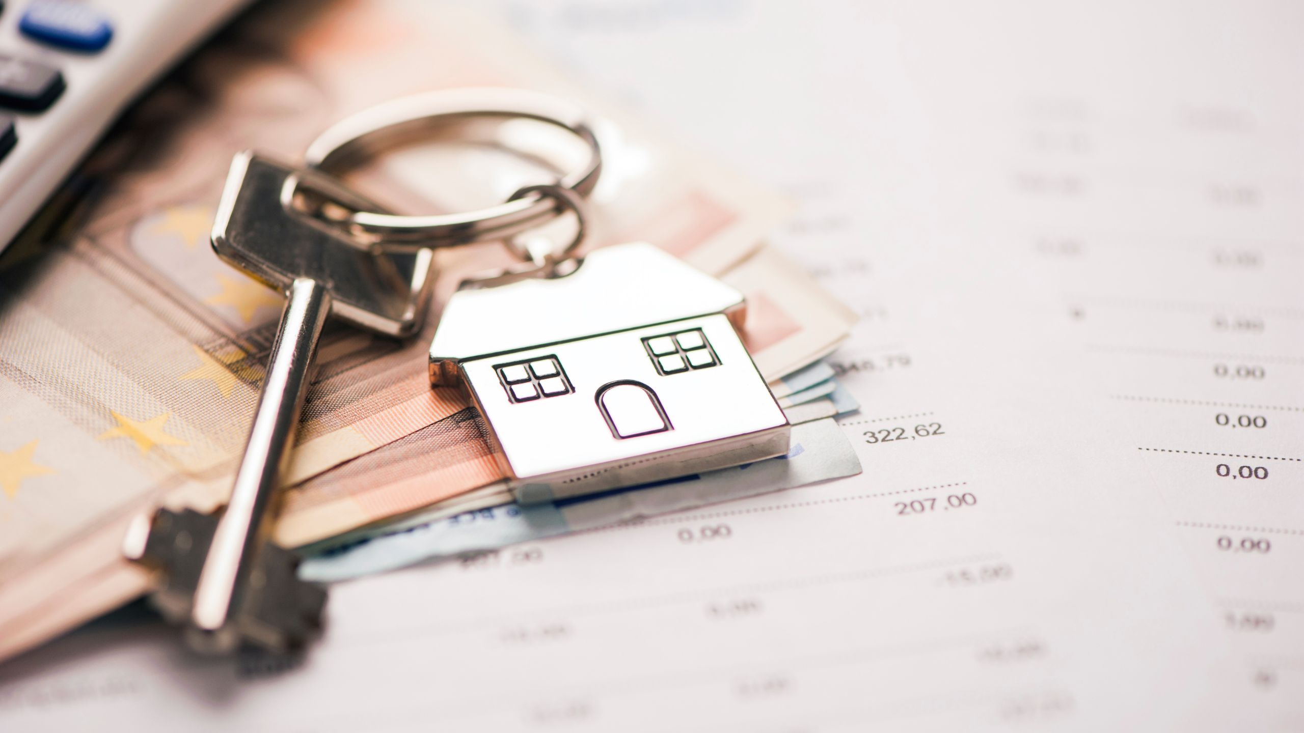 close up of calculator and small house keychain